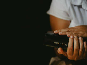 Spirituality and religion, Hands folded in prayer on a Holy Bible in church concept for faith.